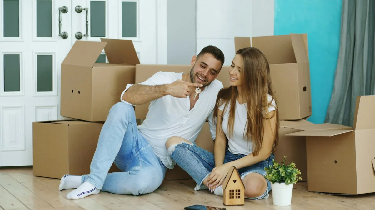 Pareja sentada entre cajas de mudanza tras comprar casa en Madrid