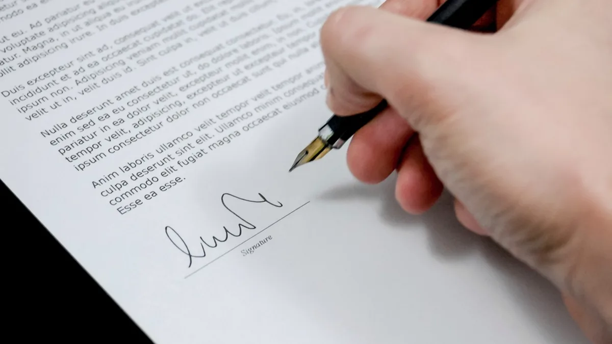 Mano firmando un documento con bolígrafo: FEIN y FiAE de la hipoteca