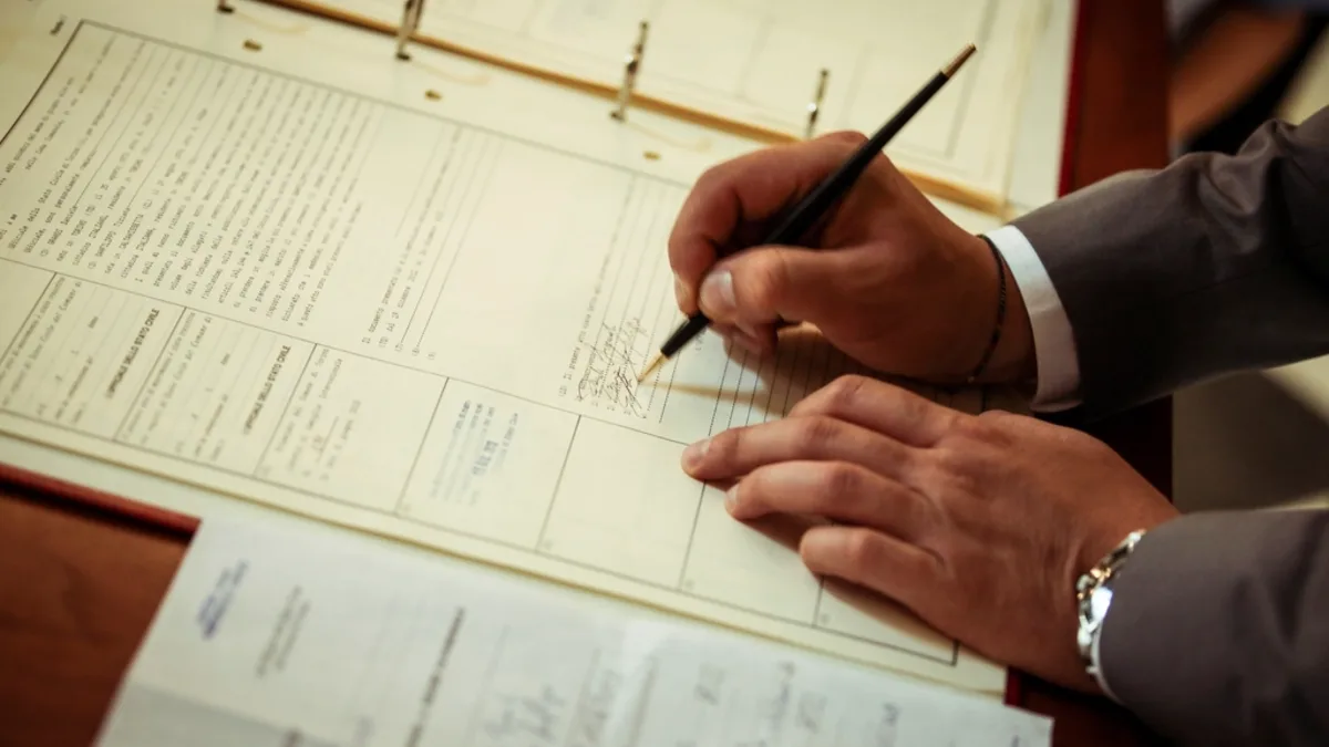 Persona firmando documentos en una mesa: firma de la hipoteca ante notario