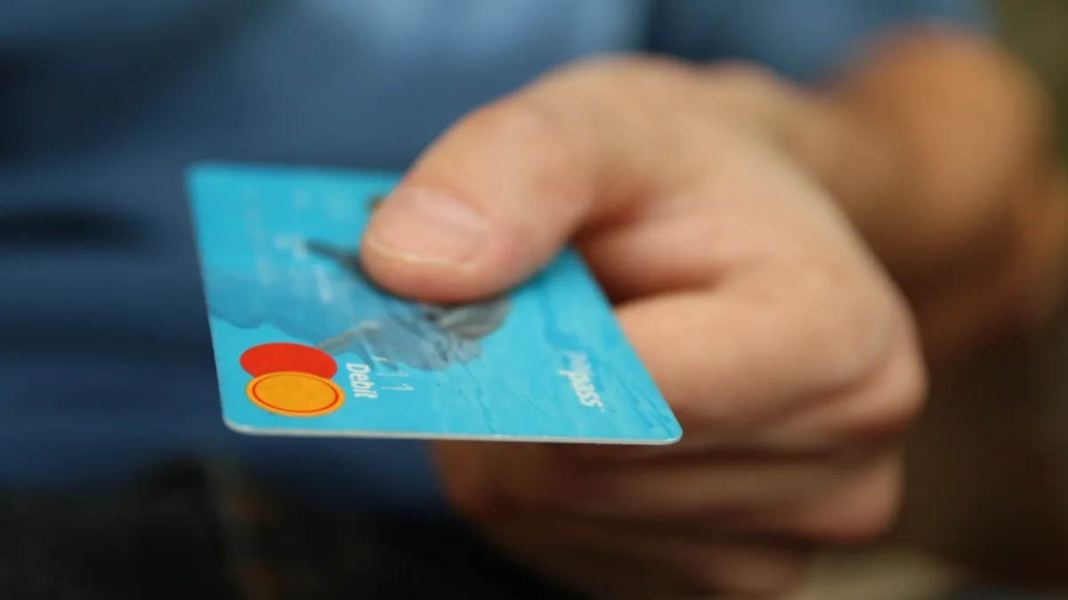 Mano entregando una tarjeta bancaria: productos vinculados a la hipoteca