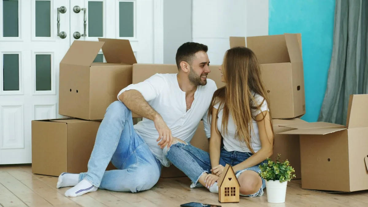 Pareja entre cajas de mudanza en su nueva casa tras cumplir los requisitos de Mi Primera Vivienda